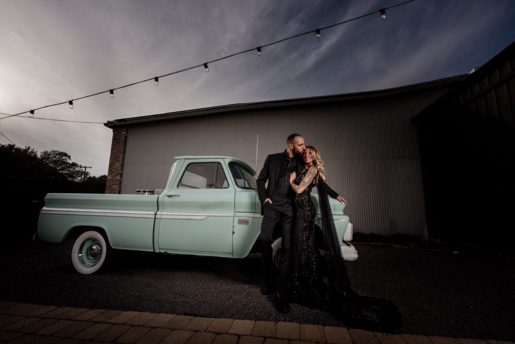 Couple portraits in front of a teal pickup truck at Warehouse 109