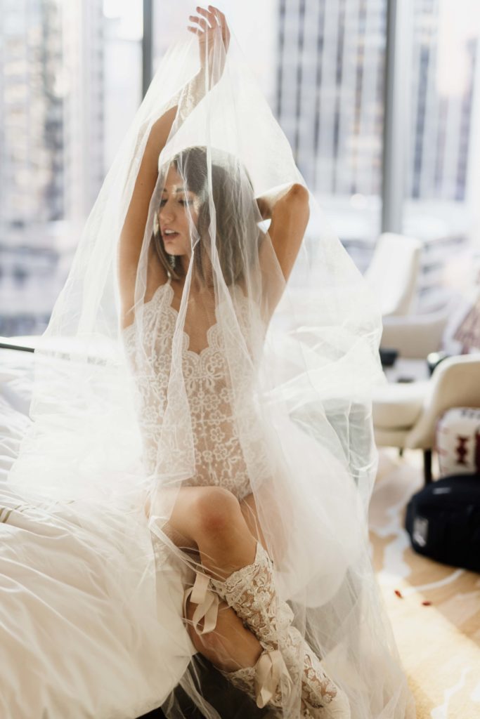 Bridal boudoir photo with the veil and a bright window behind the bride