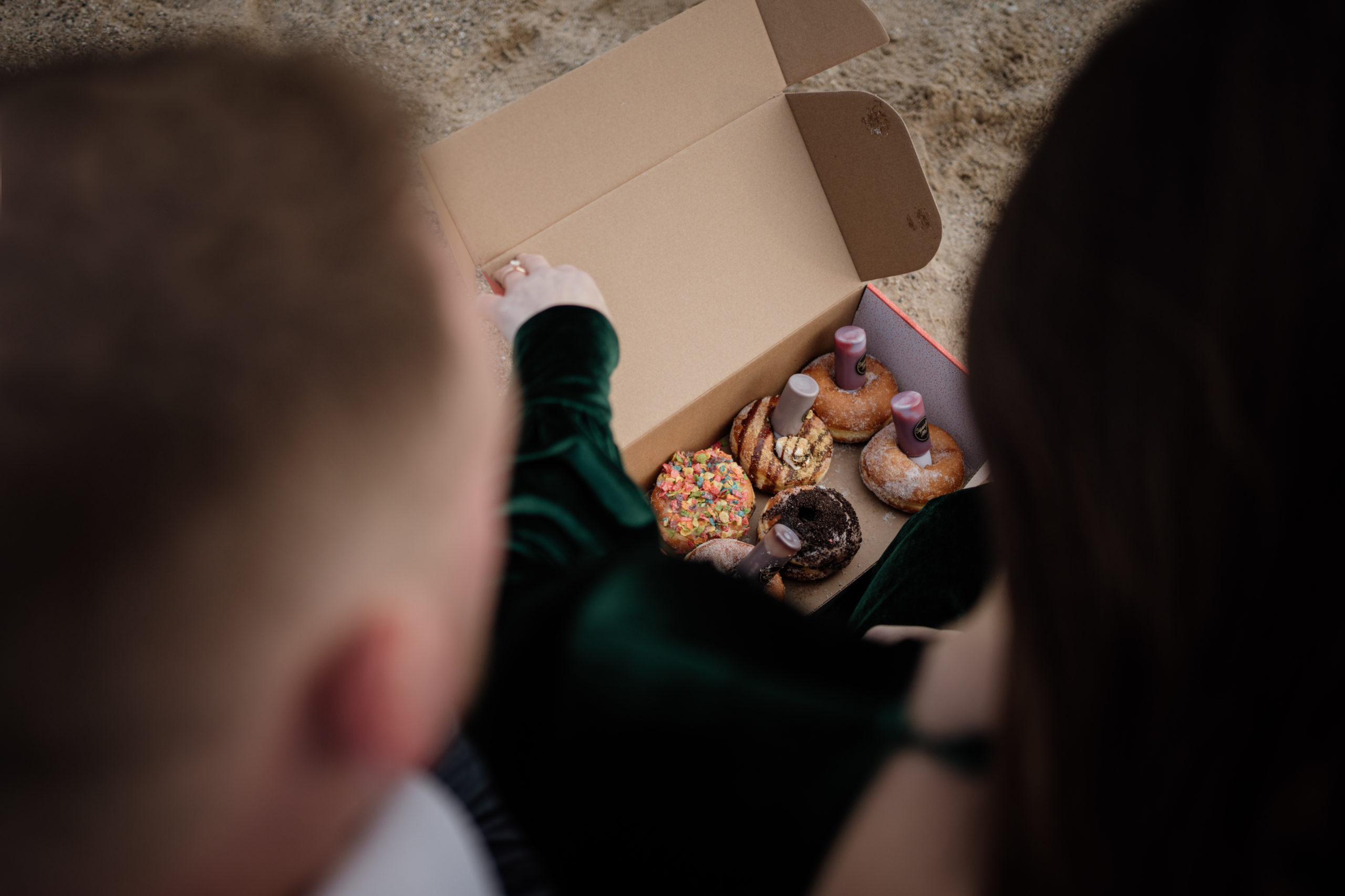 couple eating donuts at North Ave Beach for engagement photos