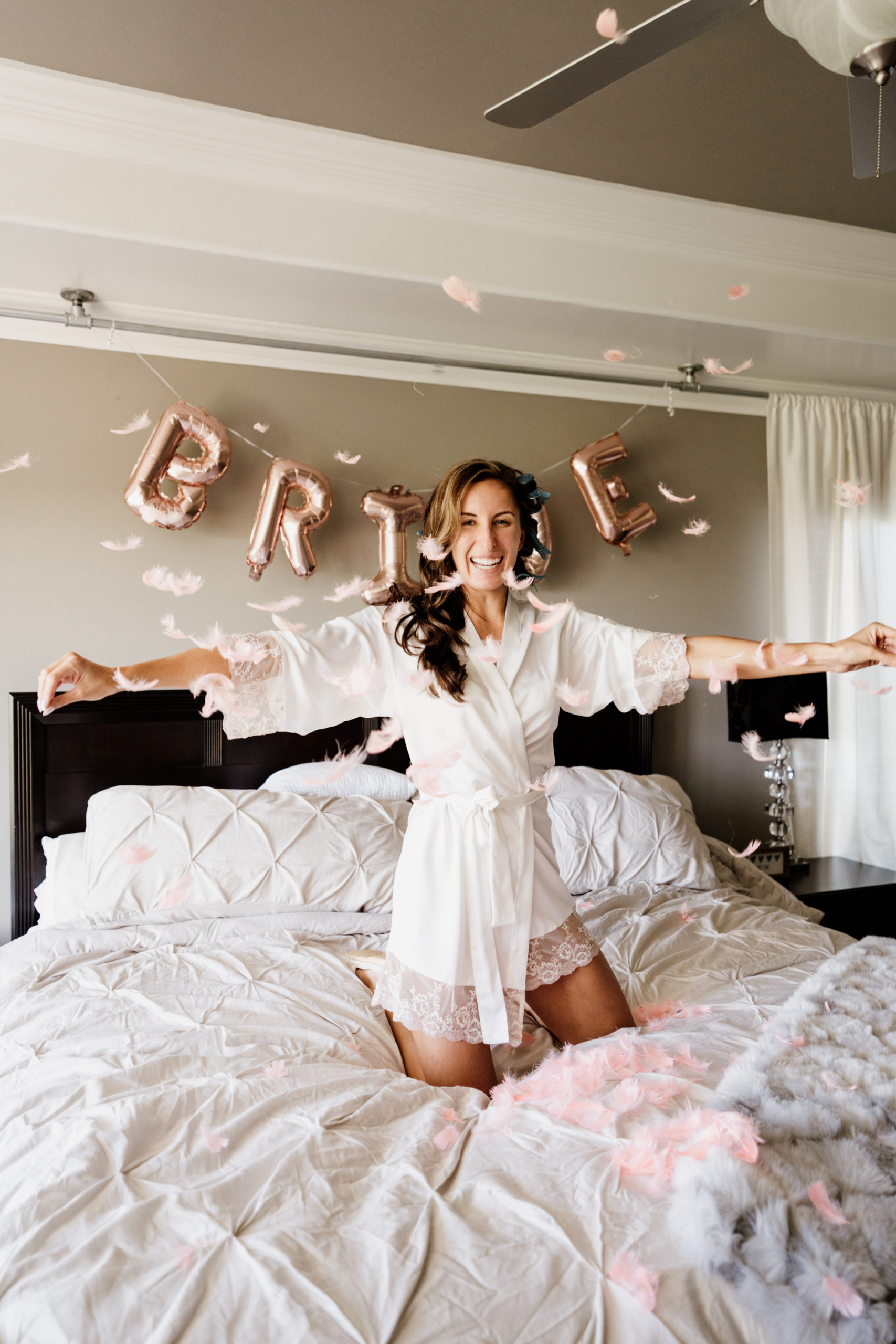 bride throwing feathers in the air as she gets ready for wedding day